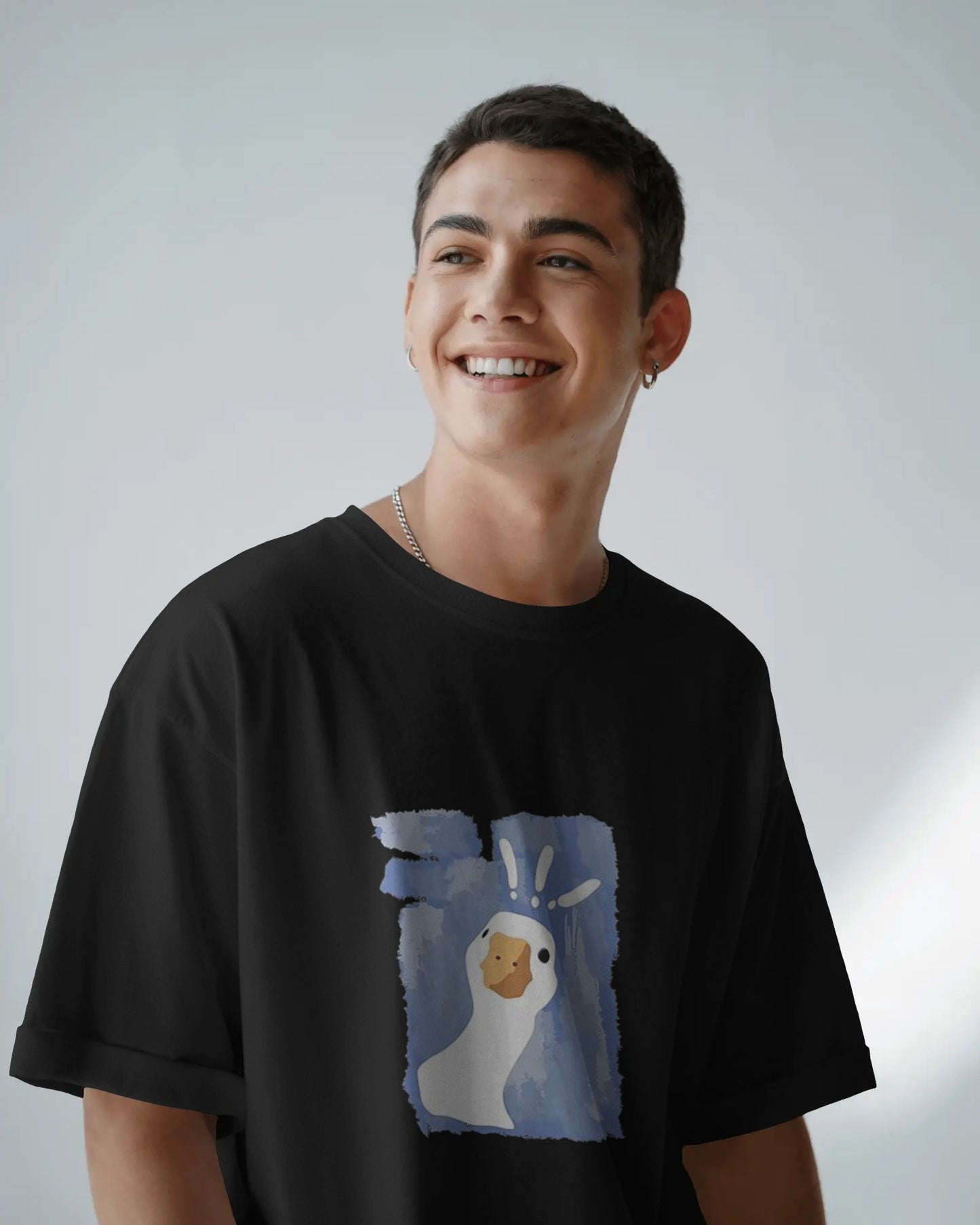 Man wearing black printed oversized unisex t-shirt with hand-drawn goose graphic, relaxed streetwear look