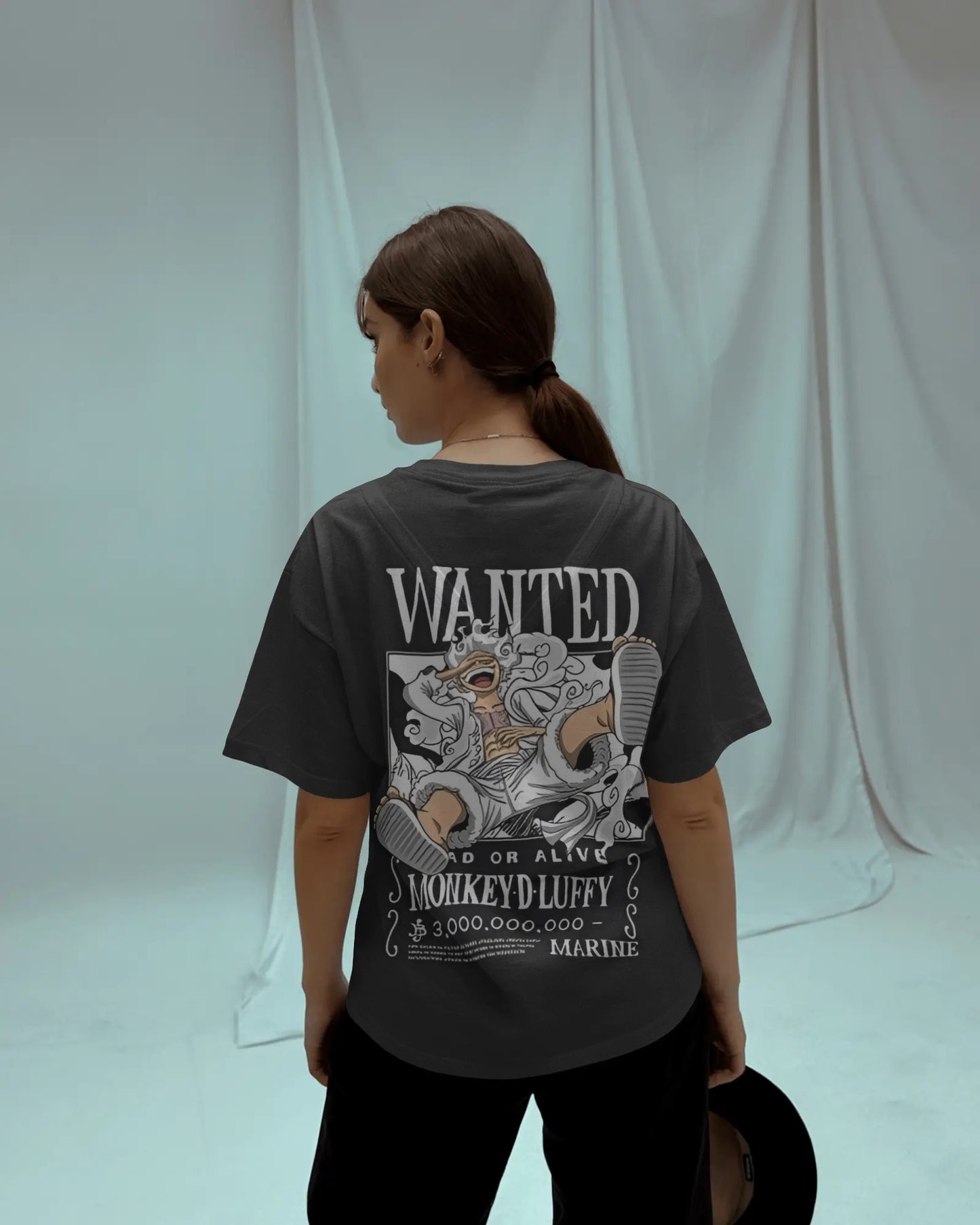 Gear 5 Awakening Nika Mode Baggy Fit Anime Tee. Model showing the back of the black tee with a large, detailed 'WANTED' poster featuring the Nika Mode anime character.